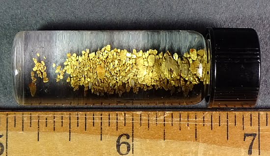 Black Hills Gold flakes enclosed in a vile with water from the Palmer Gulch area in the Black Hills of South Dakota